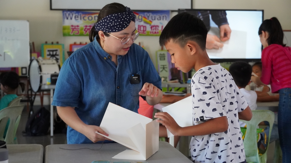 大學生協助小學生將手做書本排序