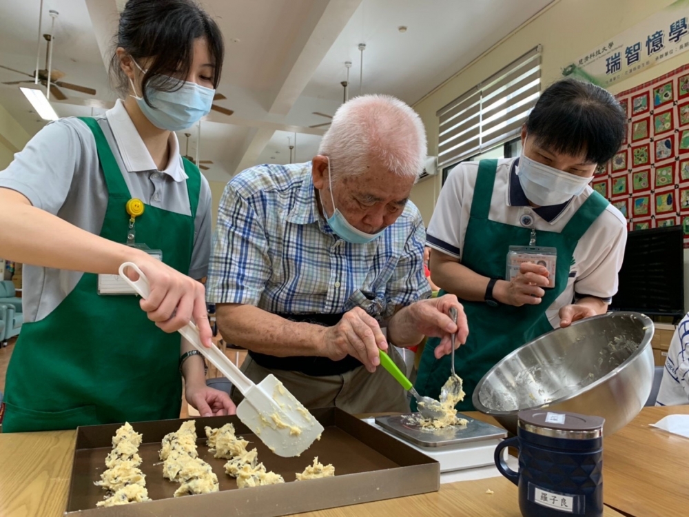 每月固定辦理「長者烘焙課程」，照片為老師及護理系學生正協助長者秤麵團重量。